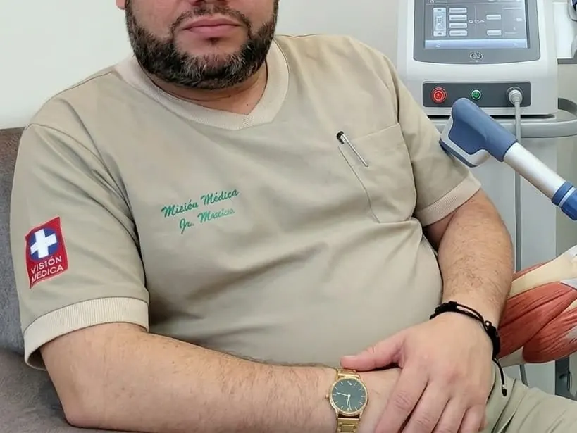 Médico junto al equipo de ondas de choque del consultorio
